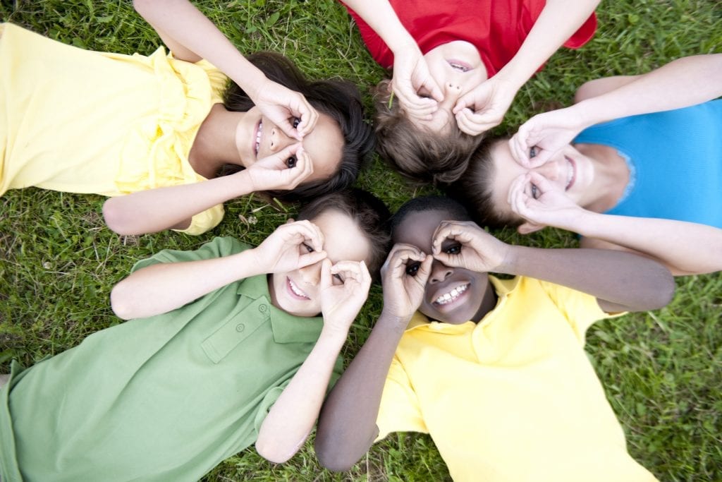 Enfants couchés en cercle faisant des lunettes avec leurs doigts