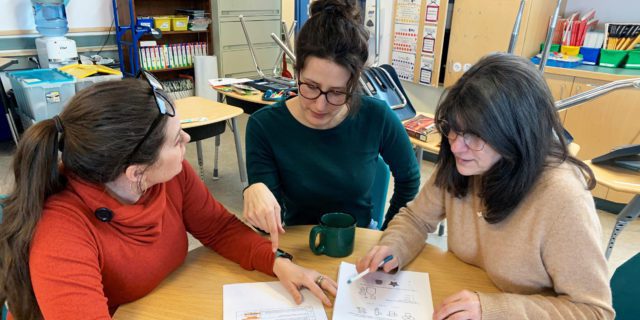 Trois enseignantes discutant autour d'une table d'un exercice à faire en classe